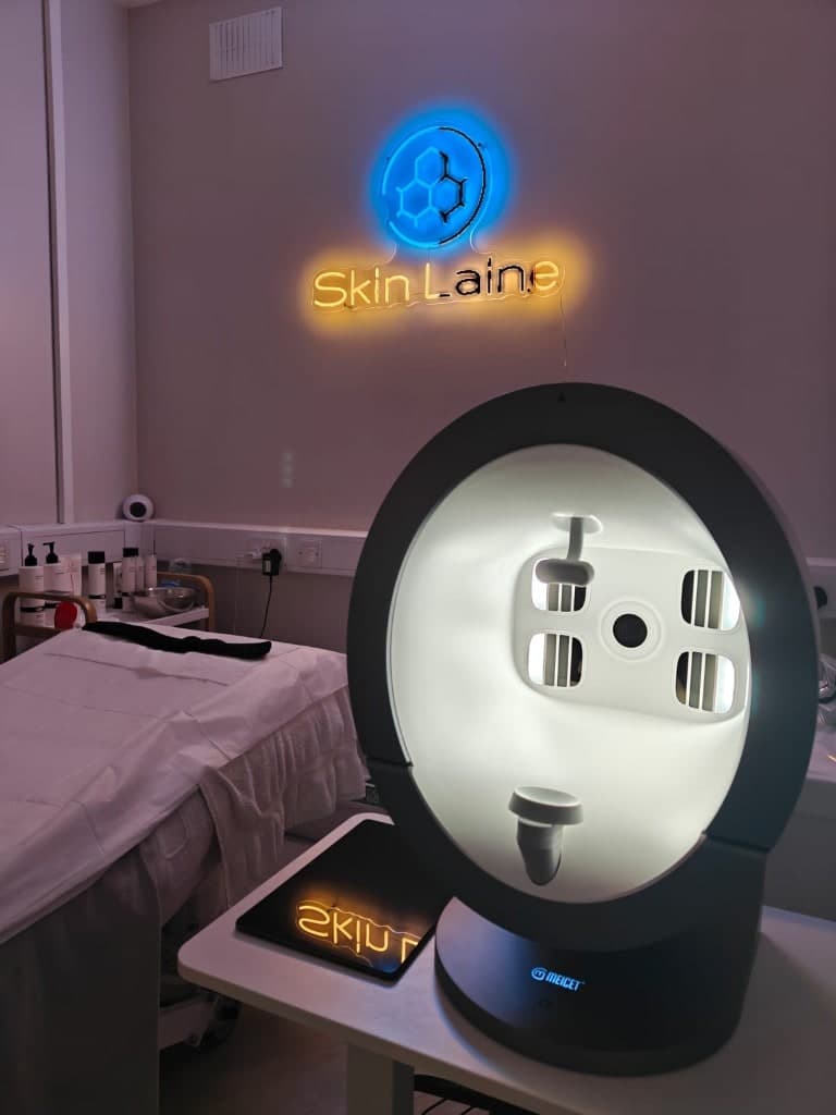 Meicet skin analysis device at Skin Laine in Ballina with the clinic’s blue and amber neon sign in the background.
